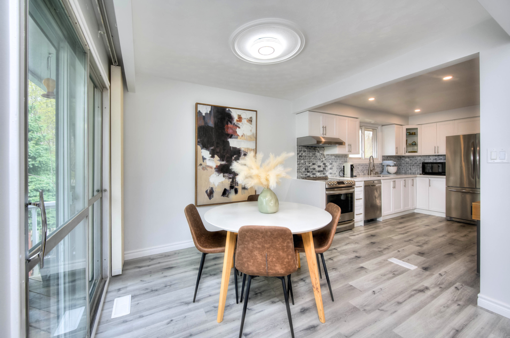 Dining area featuring a set of tables and chairs, seamlessly transitioning into a kitchen, both expertly designed and arranged by Helen's Team.