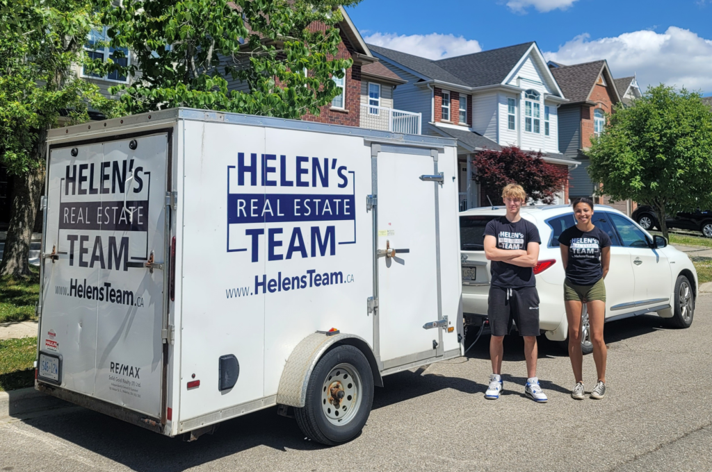 Two dedicated members of Helen's Design team, standing confidently outside a house they are staging, with the branded Helen's Design truck visible in the background, ready to transform another property.