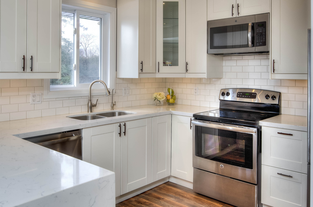 An immaculately clean, neutral-colored kitchen with modern appliances and minimalist design, showcasing an ideal example of home staging by Helen's Design.